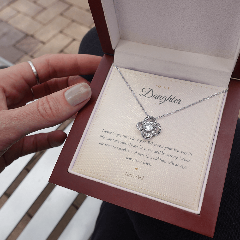 Gold love knot necklace and keepsake card in a lit mahogany gift box